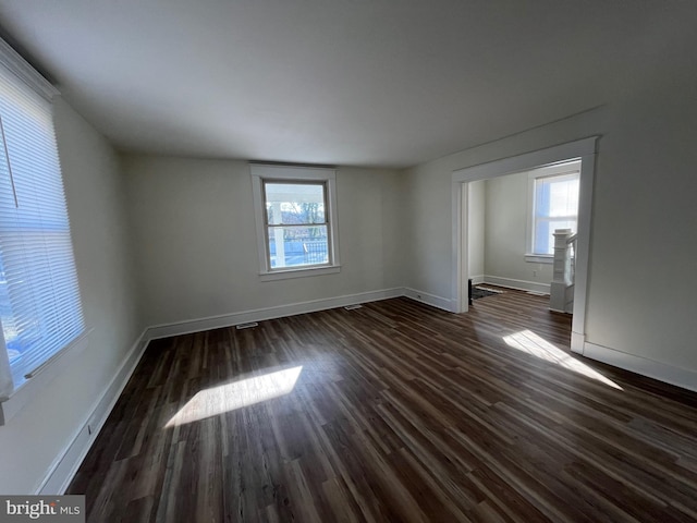 spare room with plenty of natural light and dark wood-type flooring