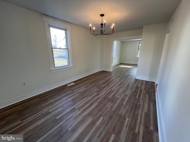 unfurnished dining area featuring a notable chandelier and dark hardwood / wood-style flooring