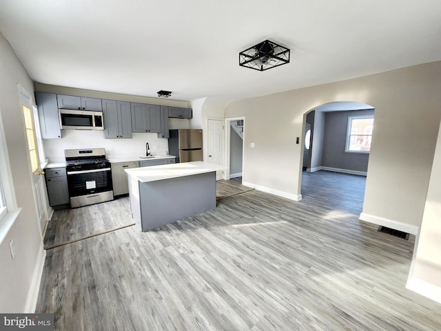 kitchen featuring gray cabinets, appliances with stainless steel finishes, sink, a center island, and light hardwood / wood-style flooring