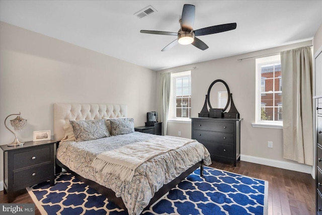 bedroom with ceiling fan, dark wood-type flooring, and multiple windows