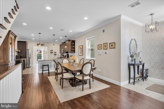 dining space with ornamental molding, a chandelier, and light wood-type flooring