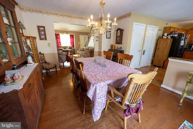 dining space featuring hardwood / wood-style flooring, an inviting chandelier, and a textured ceiling