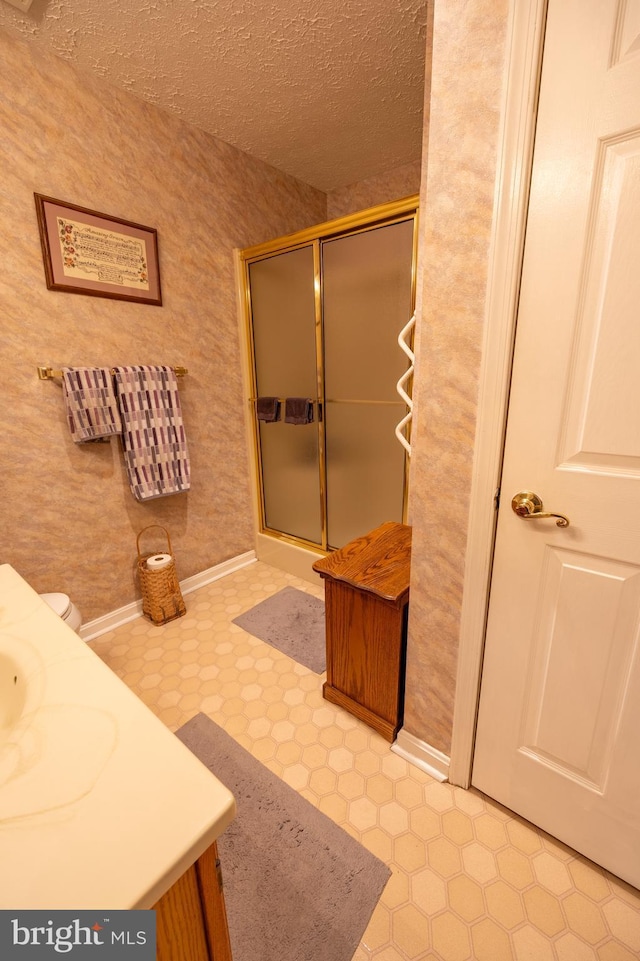 bathroom with vanity, a shower with shower door, and a textured ceiling