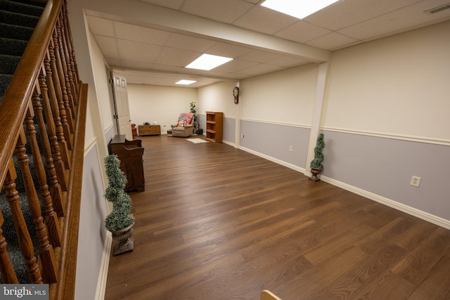 basement with a drop ceiling and dark hardwood / wood-style flooring