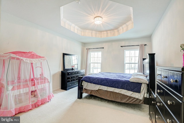 bedroom with light colored carpet and a raised ceiling