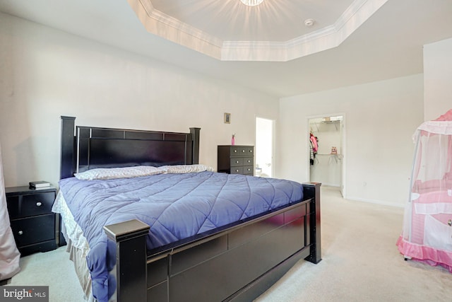 carpeted bedroom featuring a spacious closet, ornamental molding, and a raised ceiling