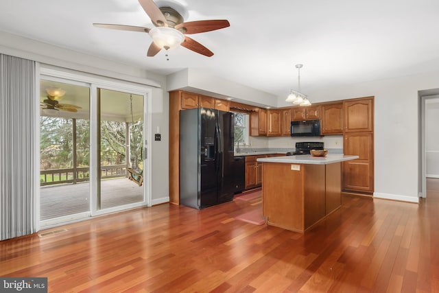 kitchen featuring a kitchen island, decorative light fixtures, dark hardwood / wood-style flooring, ceiling fan, and black appliances