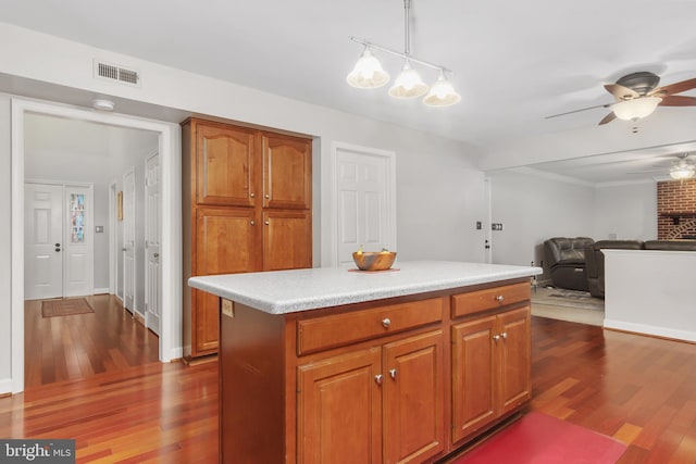 kitchen with ceiling fan, a kitchen island, dark hardwood / wood-style flooring, and hanging light fixtures