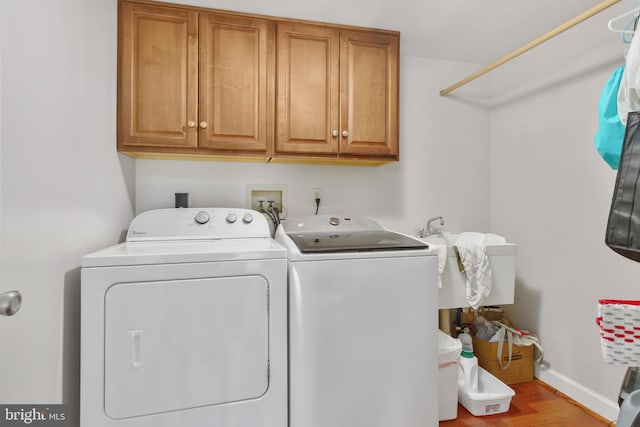 washroom with cabinets, sink, washer and dryer, and light wood-type flooring