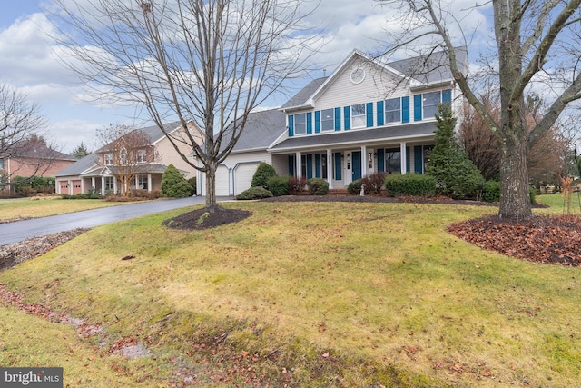 view of front of house featuring a garage, covered porch, and a front lawn