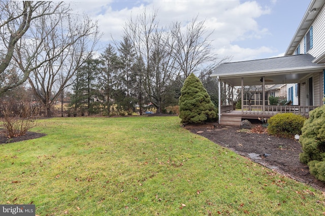 view of yard with a wooden deck and ceiling fan