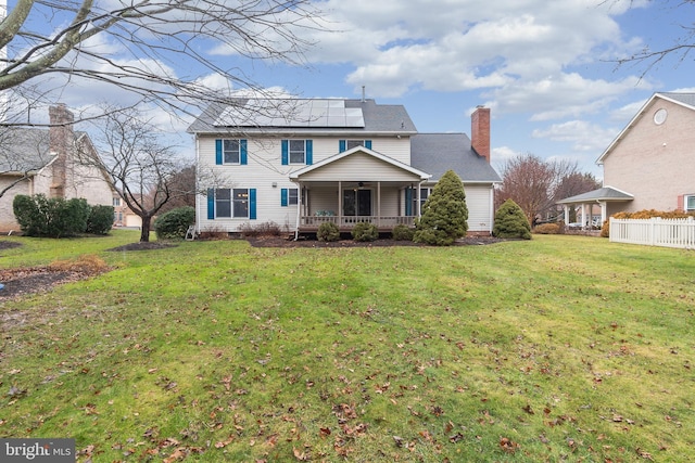 view of front of property with covered porch, a front lawn, and solar panels