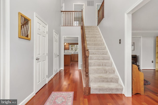 foyer featuring hardwood / wood-style flooring, crown molding, and a high ceiling