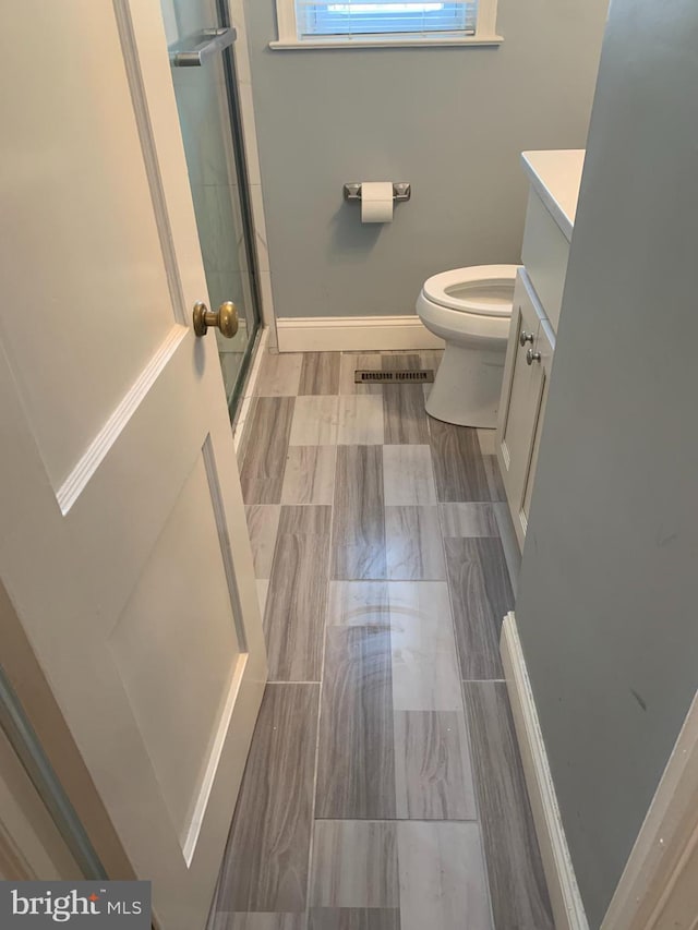 bathroom featuring vanity, toilet, and a shower with shower door