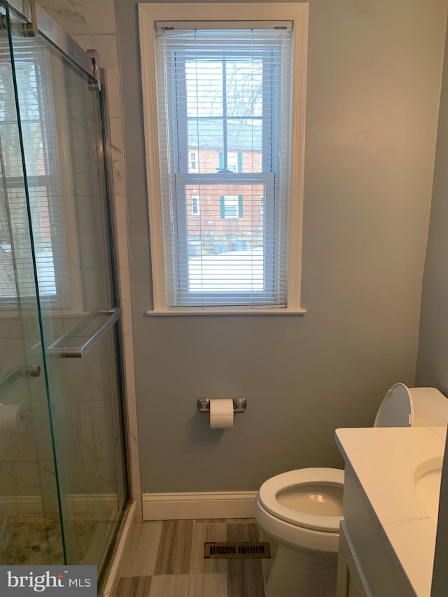 bathroom with vanity, a shower with door, and toilet