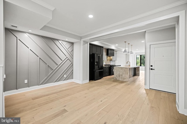 unfurnished living room featuring crown molding, sink, and light hardwood / wood-style flooring