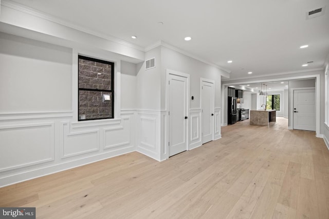 interior space with crown molding and light hardwood / wood-style floors