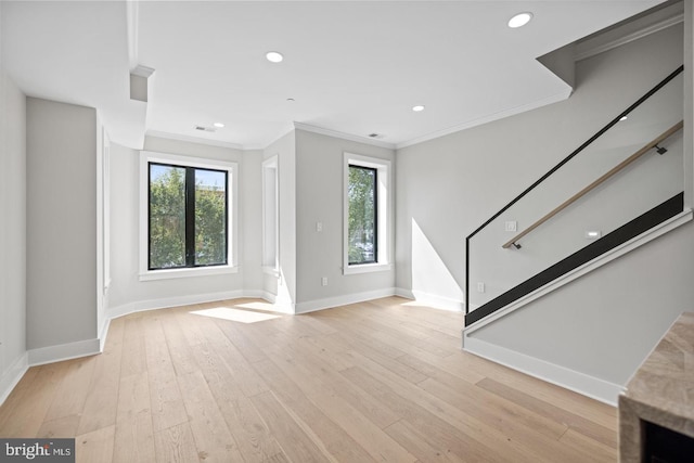 unfurnished living room with crown molding, a healthy amount of sunlight, and light hardwood / wood-style floors