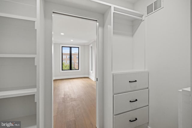 walk in closet with light hardwood / wood-style floors