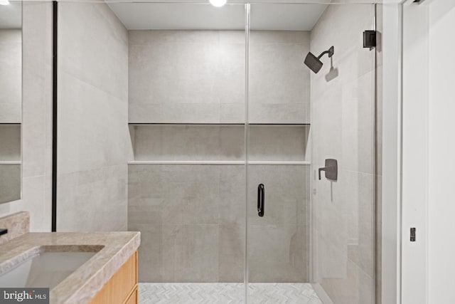 bathroom with a shower with shower door and vanity