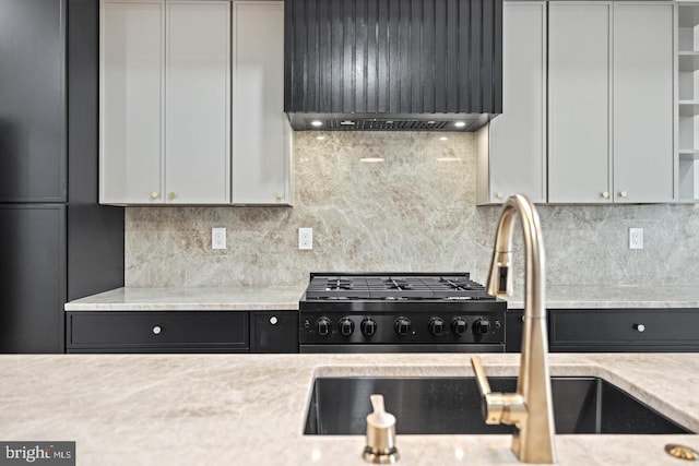 kitchen featuring custom exhaust hood, sink, white cabinets, tasteful backsplash, and light stone countertops