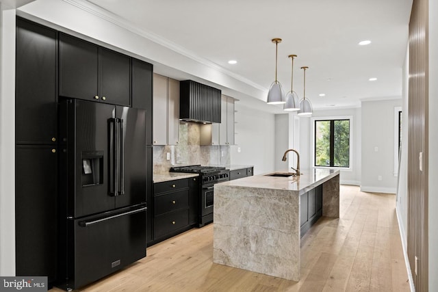 kitchen with a kitchen island with sink, sink, decorative light fixtures, gas stove, and black fridge with ice dispenser