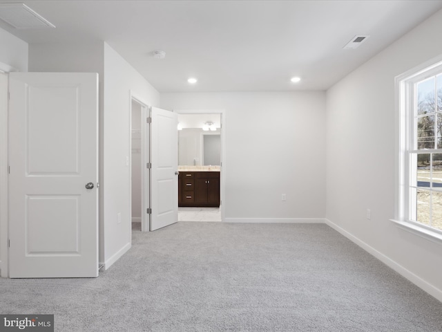 unfurnished bedroom featuring ensuite bath and light carpet