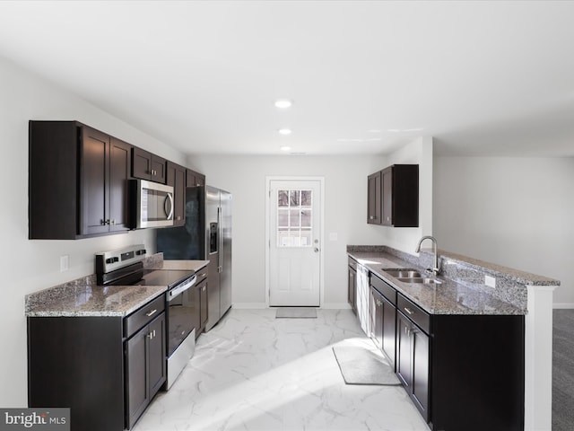 kitchen featuring sink, appliances with stainless steel finishes, dark brown cabinets, light stone countertops, and kitchen peninsula