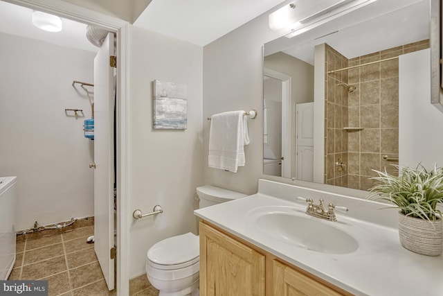 bathroom with tiled shower, vanity, and toilet