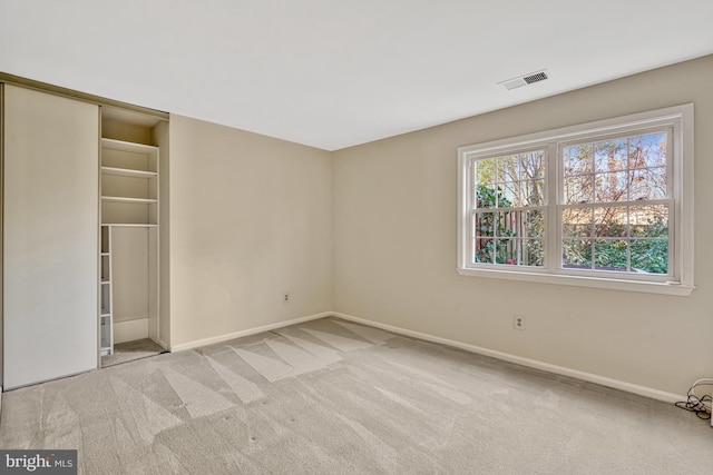 unfurnished bedroom with light carpet and a closet