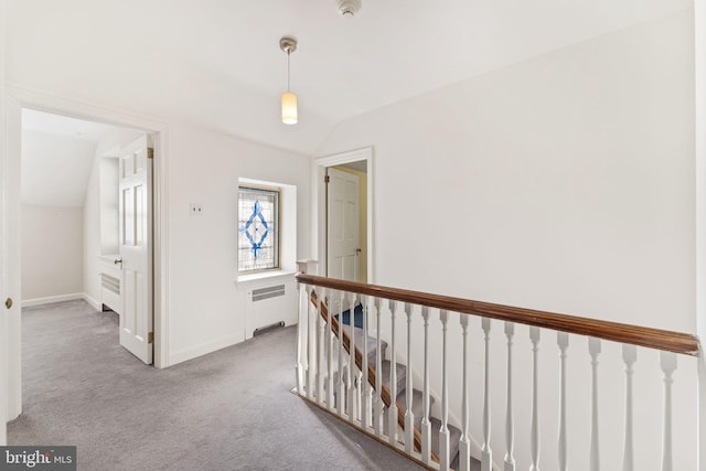 hall with lofted ceiling, radiator, and carpet