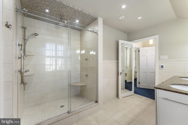 bathroom with an enclosed shower, vanity, tile patterned flooring, and tile walls