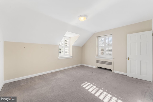 additional living space featuring lofted ceiling, radiator heating unit, light colored carpet, and plenty of natural light