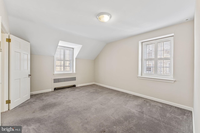 bonus room with lofted ceiling, radiator, and light colored carpet