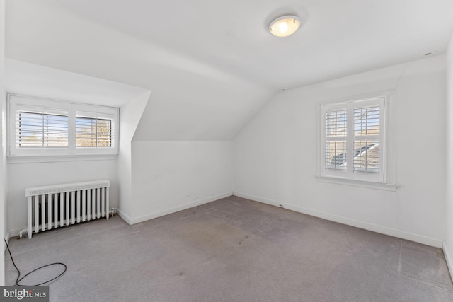 additional living space with plenty of natural light, radiator, light carpet, and lofted ceiling