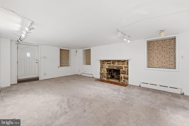 unfurnished living room with a stone fireplace, a baseboard radiator, and track lighting