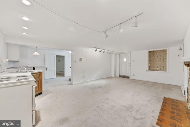 unfurnished living room with light carpet, sink, rail lighting, and a baseboard heating unit