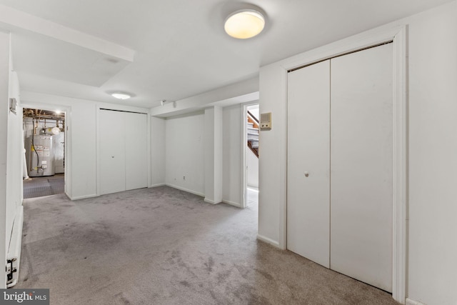 interior space with multiple closets, light carpet, and gas water heater