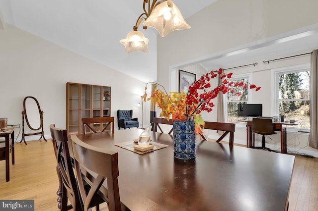 dining space with vaulted ceiling and light hardwood / wood-style flooring