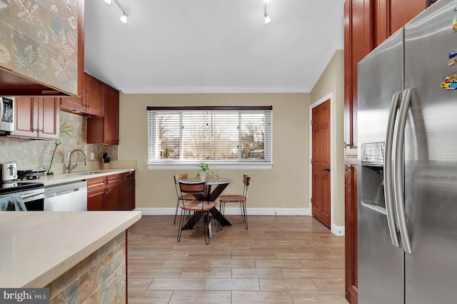 kitchen featuring backsplash, ornamental molding, stainless steel appliances, and sink