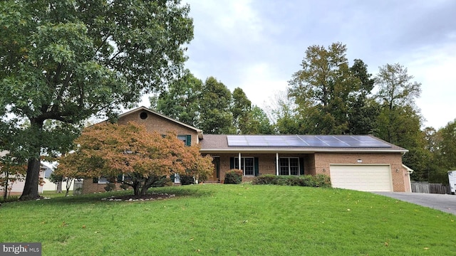 view of front of property featuring a garage, solar panels, and a front lawn