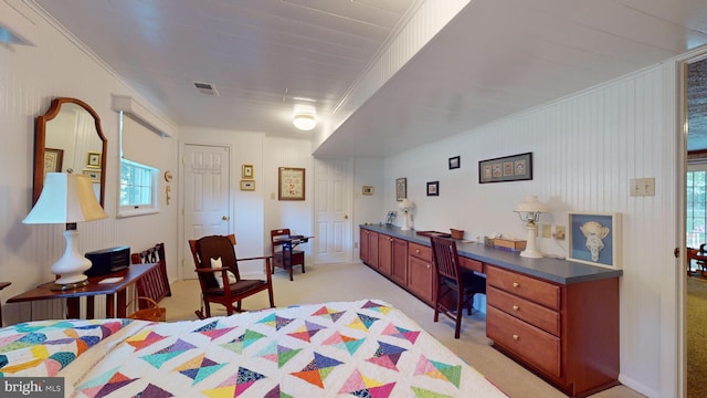 carpeted bedroom featuring multiple windows, crown molding, and built in desk