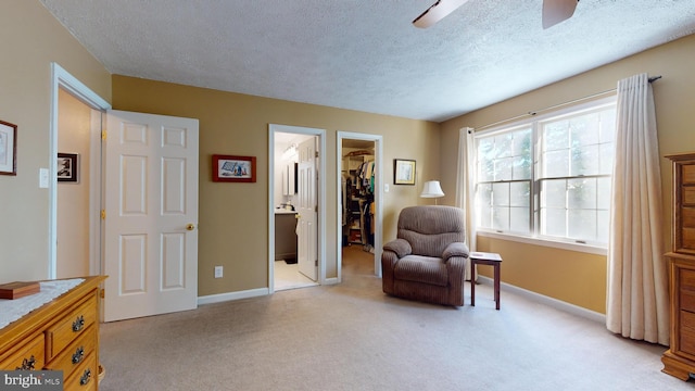 sitting room featuring ceiling fan, a textured ceiling, and light carpet