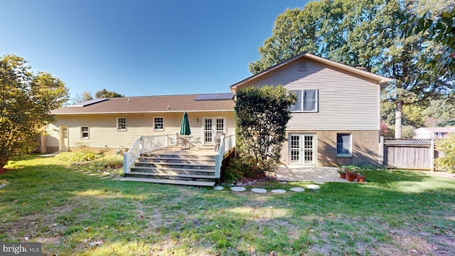 rear view of house featuring french doors, a lawn, a wooden deck, and a patio area