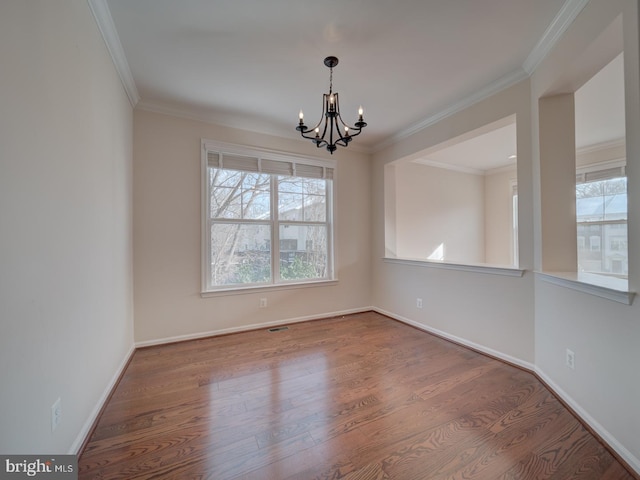 empty room featuring hardwood / wood-style flooring, crown molding, and an inviting chandelier