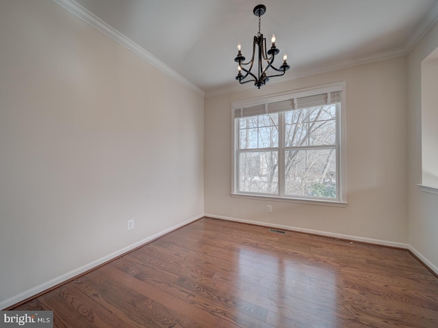 empty room with hardwood / wood-style floors, a notable chandelier, and ornamental molding