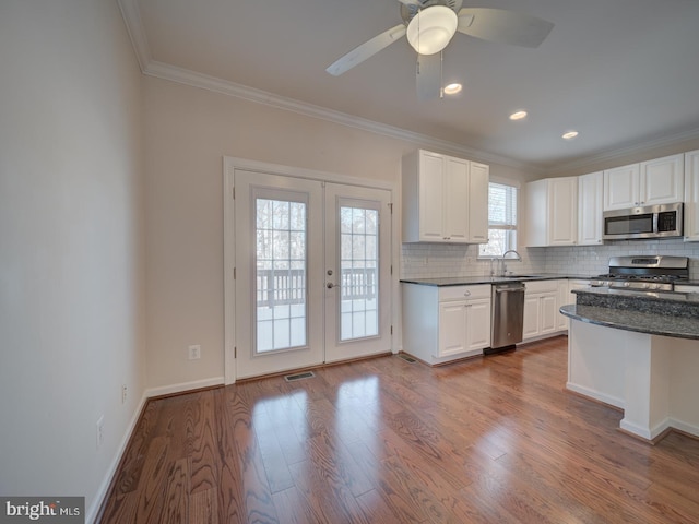 kitchen featuring french doors, ornamental molding, hardwood / wood-style flooring, stainless steel appliances, and white cabinets