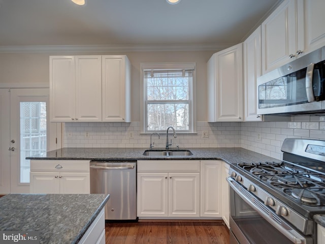 kitchen with white cabinetry, appliances with stainless steel finishes, sink, and dark stone counters