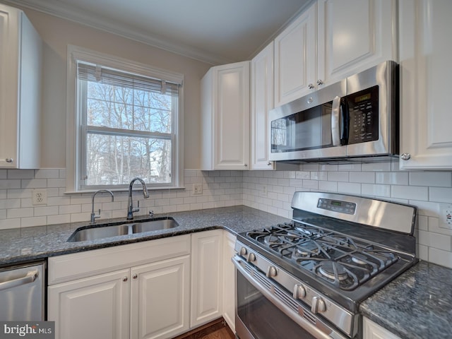 kitchen featuring sink, white cabinetry, tasteful backsplash, dark stone countertops, and stainless steel appliances