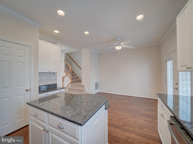 kitchen featuring white cabinetry, ornamental molding, dark stone countertops, and a kitchen island